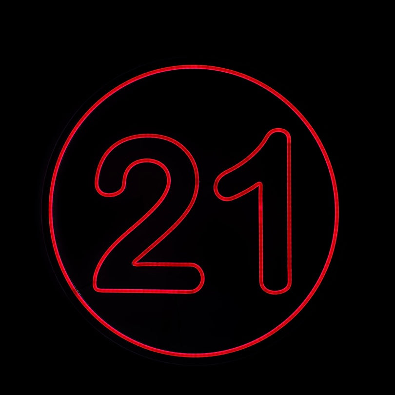 round red bold 21 neon sign with a bright circle border on a black back ground