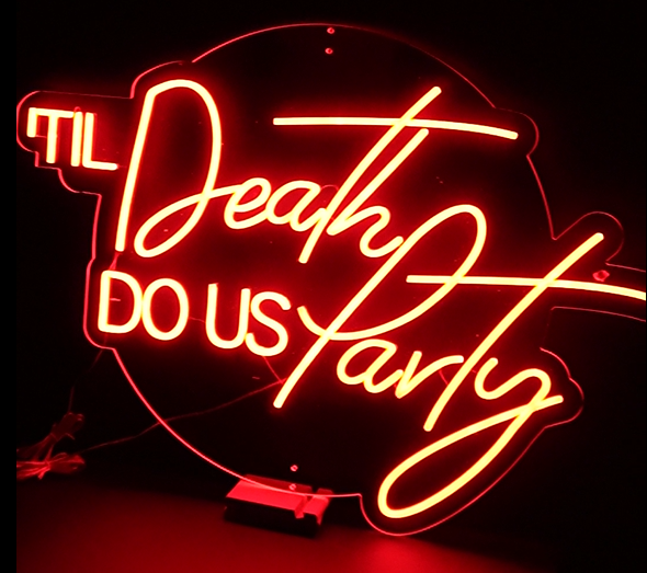 An LED neon sign with a red glow, featuring the text 'Til Death Do Us Party in a playful, cursive font against a black background.