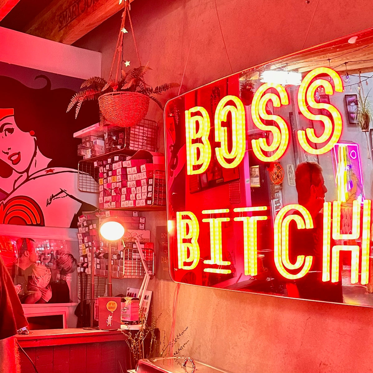 Yellow and red neon sign reading Boss Bitch in a red-lit shop