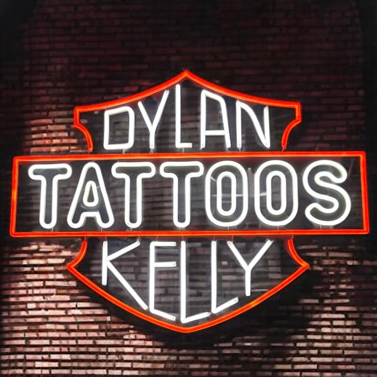 Red and white neon sign reading Dylan Kelly Tattoos on a brick wall