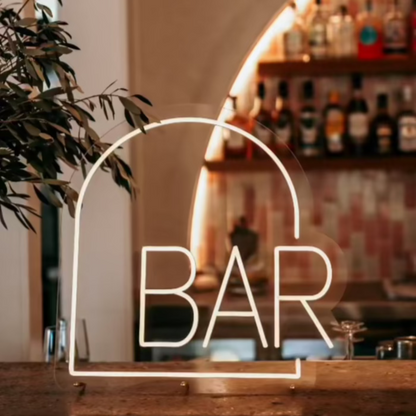 arch shape warm white neon sign sitting on a concrete bar 