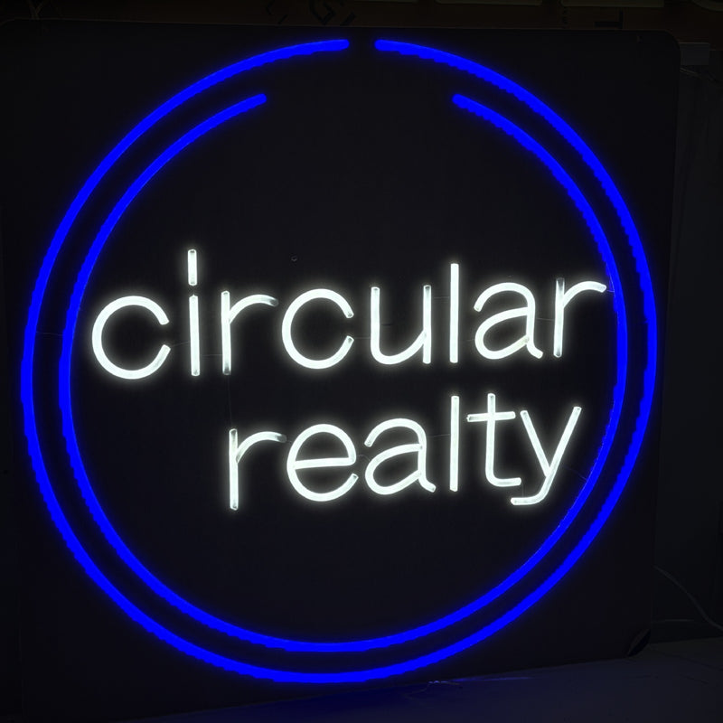 Circular Realty logo neon sign, white lettering inside a blue ring