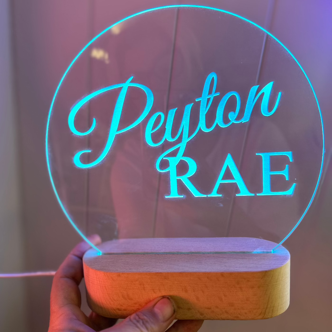 blue led lit night light with the name Peyton Rae engraved into the acrylic top with a oval timber base