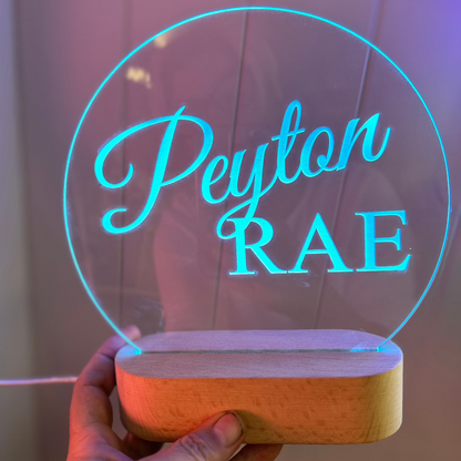 blue led lit night light with the name Peyton Rae engraved into the acrylic top with a oval timber base