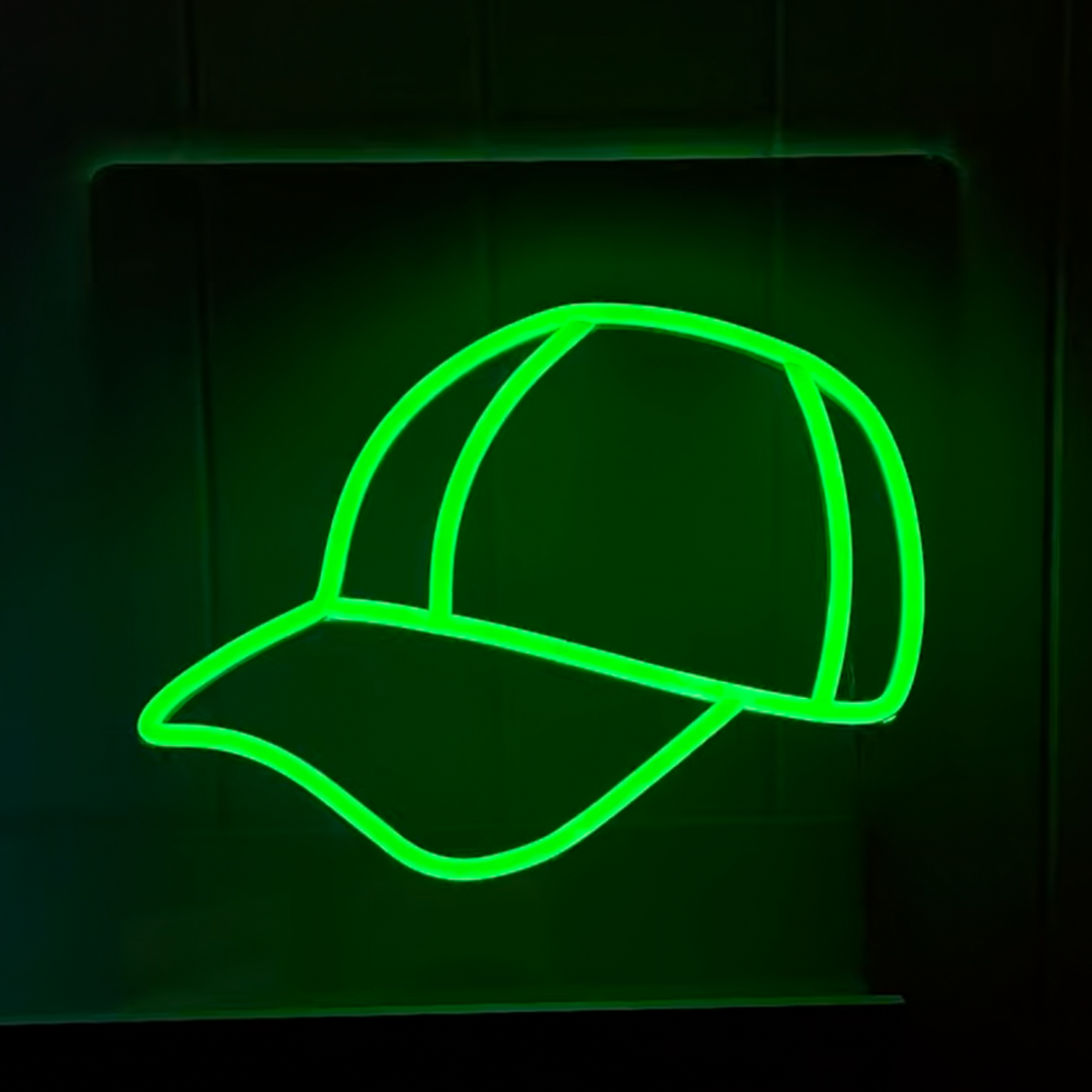 bright green neon baseball cap glowing brightly against a black wall
