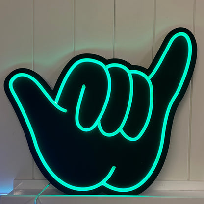 green neon shaka hand neon on a matte black backing board