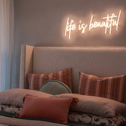 a warm glow form the life is beautiful neon light, mounted abve a beautifl rustic look bedroom display