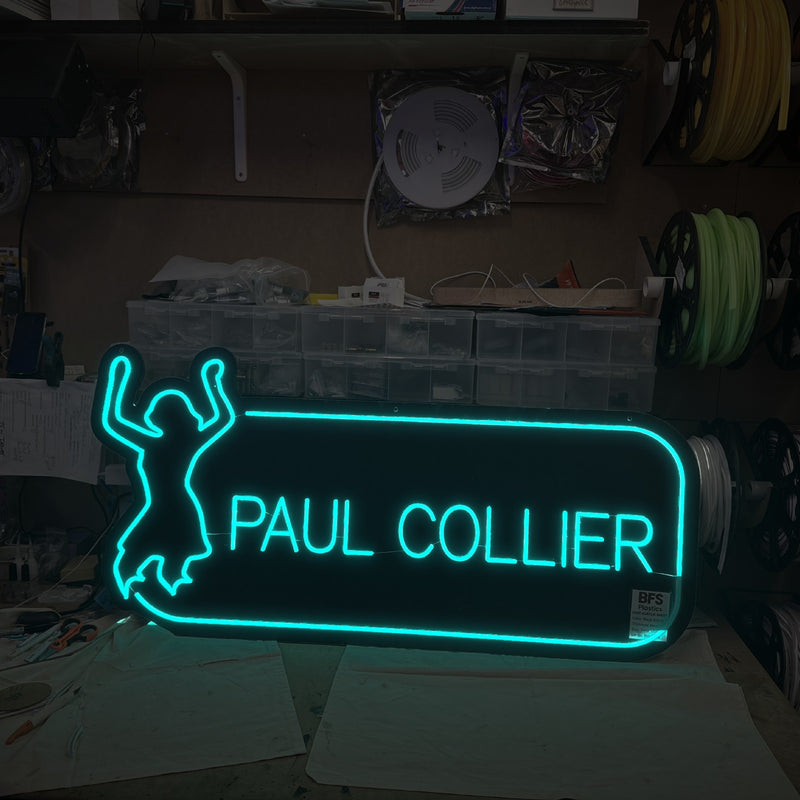 Paul Collier logo neon sign in aqua with a dancing figure