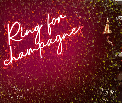 Neon sign with 'Ring for Champagne' text on a leafy background