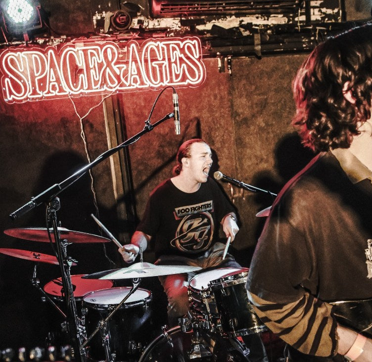 Space & Ages LED neon sign above a band playing live